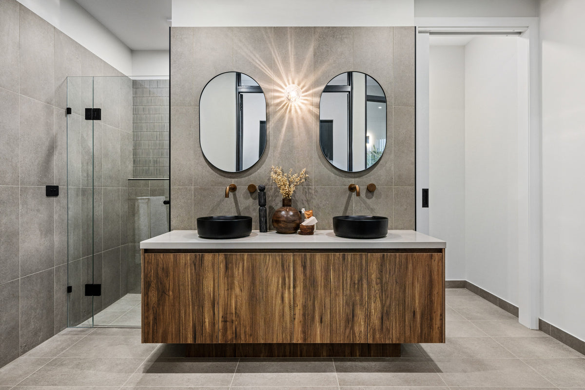 Modern bathroom with wooden vanity, round mirrors, and decorative items.